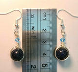 Image of a pair of earrings with round Blue Sandstone beads wrapped with silver wire and topped with blue Swarovski crystals against a ruler measuring 1 1/2 inches