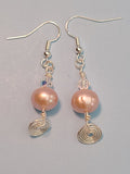 Image of a pair of earrings with a 10mm freshwater pearl topped with a clear crystal and a circular spiral of silver wire hanging below