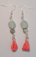 Image of a pair of earrings one with aqua colored recycled glass beads from Ghana, tree of life beads and pink tassels hung on silver wire