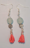 Image of a pair of earrings one with aqua colored recycled glass beads from Ghana, tree of life beads and pink tassels hung on silver wire