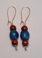 Image of a pair of earrings with blue colored recycled glass from Ghana with blood sandalwood beads over and under the glass bead on copper wire