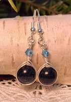 Image of round Blue Sandstone beads wrapped with silver wire and topped with blue Swarovski crystals hanging from birch bark in front of pine branches and an artificial snowflake