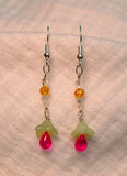 Image of light green and hot pink flowers topped by clear and orange glass beads hung from Silver hooks on white cloth earrings