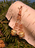 Image of copper earrings with jasper round beads and clear Austrian crystals hanging from birch bark