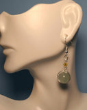 Image of a Green Aventurine earring wrapped by silver wire topped by a daisy bead and yellow Swarovski crystal hanging from a mannequin