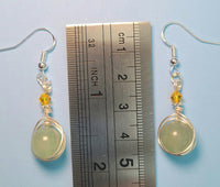 Image of a pair of Green Aventurine earrings wrapped by silver wire topped by a daisy bead and yellow Swarovski crystals against a ruler measuring 1 3/4 inches