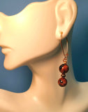 Image of a mannequin wearing an earring of Bicolored Sandstone beads separated by a copper bead