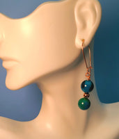 Image of a mannequin wearing an earring of Phoenix beads separated by a copper bead