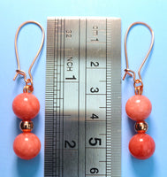 Image of earrings of Pale Red Chalcedony beads separated by a copper bead pictured with a ruler measuring 2 1/4 inches