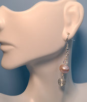 Image of an earring with a 10mm freshwater pearl topped with a clear crystal and a circular spiral of silver wire hanging below on a mannequin