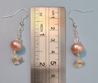 Image of a pair of earrings with a 10mm freshwater pearl topped with a clear crystal and a circular spiral of silver wire hanging below next to a ruler measuring 2 inches long