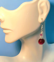 Image of an earring with pink tiger eye 10mm beads wrapped by silver wire and topped by a pink 4mm Swarovski crystal on a mannequin