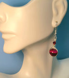 Image of an earring with pink tiger eye 10mm beads wrapped by silver wire and topped by a red 4mm Swarovski crystal on a mannequin