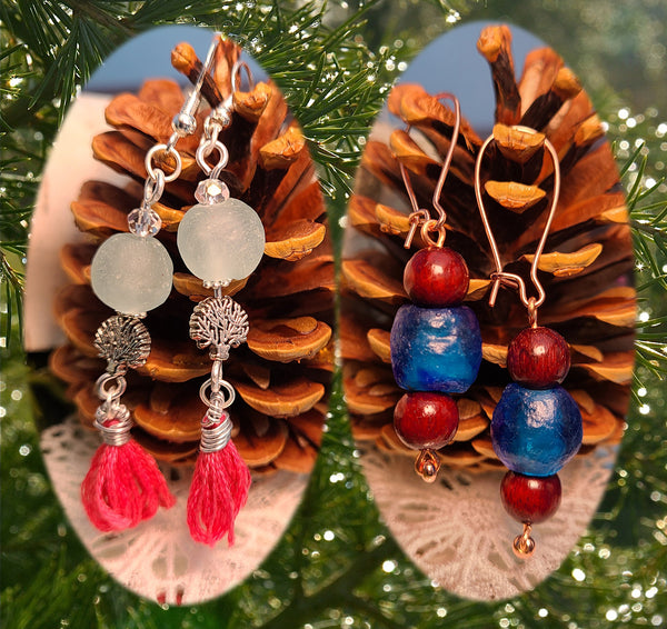 Image of 2 pairs of earrings one with aqua colored recycled glass beads from Ghana, tree of life beads and pink tassels hung on silver wire, the second with blue colored recycled glass from Ghana with blood sandalwood beads over and under the glass bead on copper wire