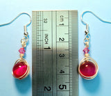 Image of 1 pair of earrings with pink tiger eye 10mm beads wrapped by silver wire and topped by a pink 4mm Swarovski crystal by a ruler measuring 1 3/4"